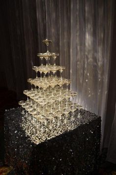 a black table topped with lots of wine goblets filled with liquid and bubbles