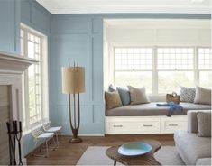 a living room with yellow walls and blue trim on the windows, white couches and coffee table