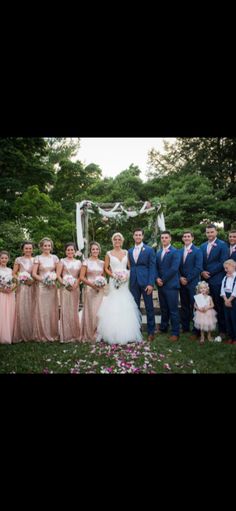 a group of people standing next to each other in front of some trees and flowers