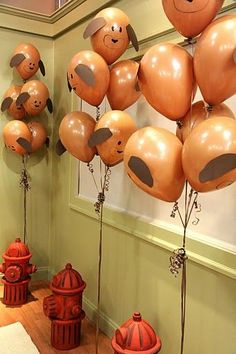 there are many balloons in the shape of faces on this room's wall and fire hydrant