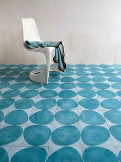 a white chair sitting on top of a blue floor next to a table with a blanket