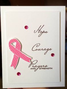 a hand holding up a card with a pink ribbon on it