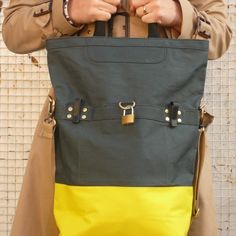 a person holding a large bag in their hands with two locks on the front pocket