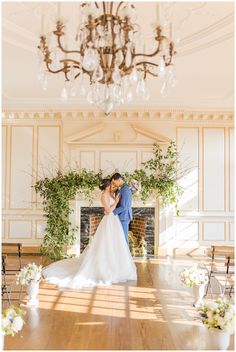 a bride and groom standing in front of a fireplace with greenery on the mantle