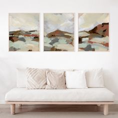 two paintings hang on the wall above a couch