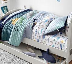 a child's bed with blue and white bedspread, pillows and toys