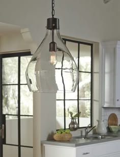 a kitchen area with a sink, stove and light hanging from the ceiling in front of windows