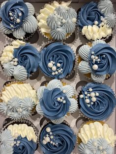 blue and white cupcakes are arranged in a box