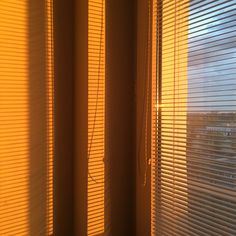 the sun is shining through some blinds in this room with no curtains on either side