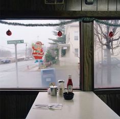 a table with two cups and bottles on it in front of a window that has christmas decorations hanging from the windows