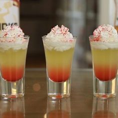 three shot glasses filled with drinks on top of a table