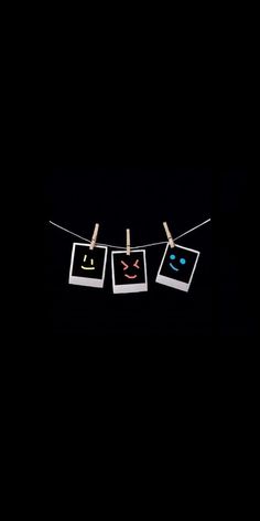 three pictures hanging on a clothes line with clothes pins in the shape of smiley faces