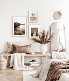 a white room with pictures on the wall and a bench in front of some pillows