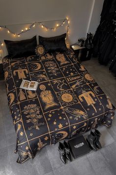 a bed covered in black and gold sheets with lights on the headboard above it