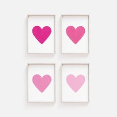 four pink hearts are arranged in square frames on a white wall, each with a different color