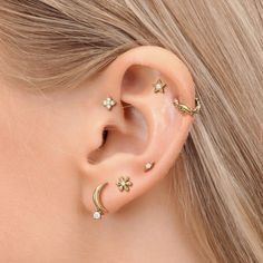 a close up of a person's ear with gold stars and moon piercings