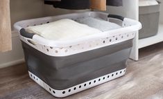 a gray and white laundry basket sitting on top of a wooden floor