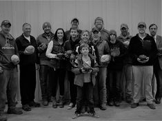 a group of people standing next to each other in front of a wall holding baseballs