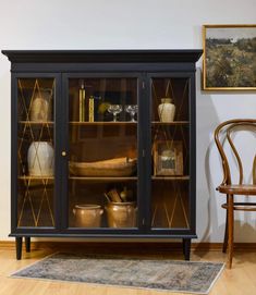 a black china cabinet with glass doors and shelves