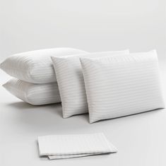 four pillows stacked on top of each other in front of a white background with one folded pillow