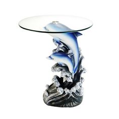 a glass table with dolphins on it and some rocks in the water under it, against a white background