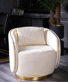 a white and gold chair sitting on top of a hard wood floor next to a potted plant