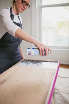 a woman in an apron painting a wooden table