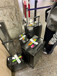 several suitcases are stacked on top of each other in an airport lobby with luggage tags attached to them