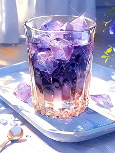 a glass filled with purple ice sitting on top of a white tray next to flowers