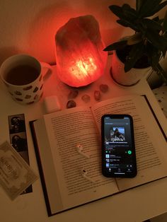 an open book sitting on top of a table next to a cell phone