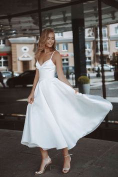 a woman in a white dress is posing for the camera