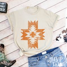 a t - shirt with an orange and white design on it next to some denim shorts