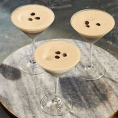 three martinis with coffee beans in them on a marble table