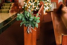 a church pew with flowers and greenery in the foreground, lit by christmas lights