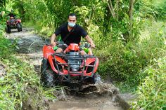 a man riding on the back of an orange four - wheeler through mud and brush