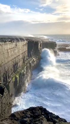 a man standing on top of a cliff next to the ocean