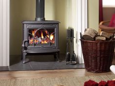 a wood burning stove in a living room next to a basket full of firewood