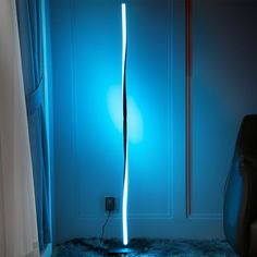 a floor lamp that is on top of a rug in front of a blue wall