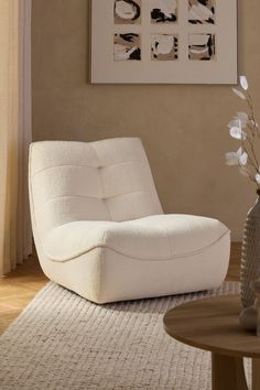 a white chair sitting on top of a rug next to a vase filled with flowers