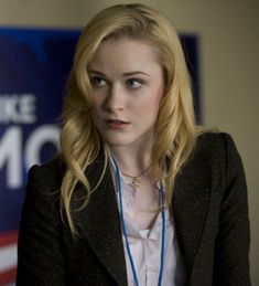 a woman with blonde hair wearing a black blazer and white shirt is looking at the camera