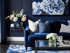 a living room with blue couches and flowers in vases on the coffee table