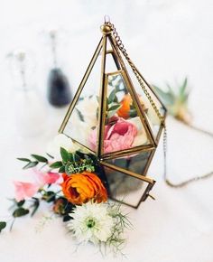 an ornament filled with flowers sitting on top of a white table covered in greenery