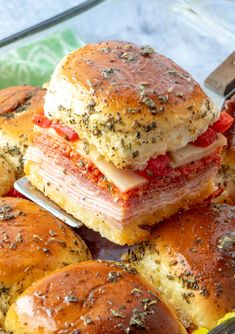 ham and cheese sliders stacked on top of each other in a baking dish with a spatula