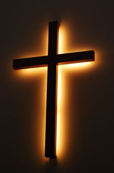 a cross lit up in the dark with light coming from it's back end