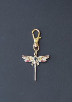 a keychain with a dragonfly design on it's side and a metal hook