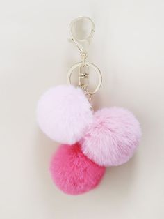 two pink and white pom - poms hanging from a keychain