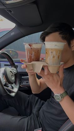 two people sitting in a car holding up cups