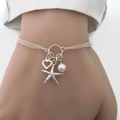 Perfect for a sea lover/sailor/beach wedding. A cute detailed starfish, tiny heart and freshwater pearl charm bracelet in sterling silver. Details: - Material metal: sterling silver - Starfish charm measures 15mm. - Heart charm measures approx. 7mm - Freshwater pearl measure 6-7mm - Adjustable Cheap Silver Charm Bracelet For Beach, Ocean-inspired Bracelet With Starfish Charm, Ocean-inspired Starfish Charm Bracelet, Elegant Starfish Bracelets For Beach, Elegant Starfish Bracelet For Gift, Ocean-inspired Starfish Charms Jewelry, Silver Nautical Bracelets As A Gift, Adjustable Silver Jewelry With Starfish Charm, Starfish Charm Bracelet As Gift