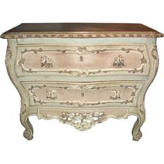 an antique chest with drawers and carvings on the front, painted in white and gold