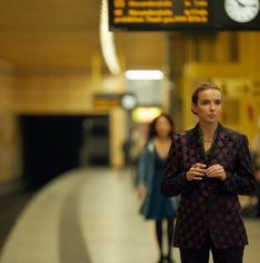 a woman is standing in the middle of a train station with her hands clasped to her chest